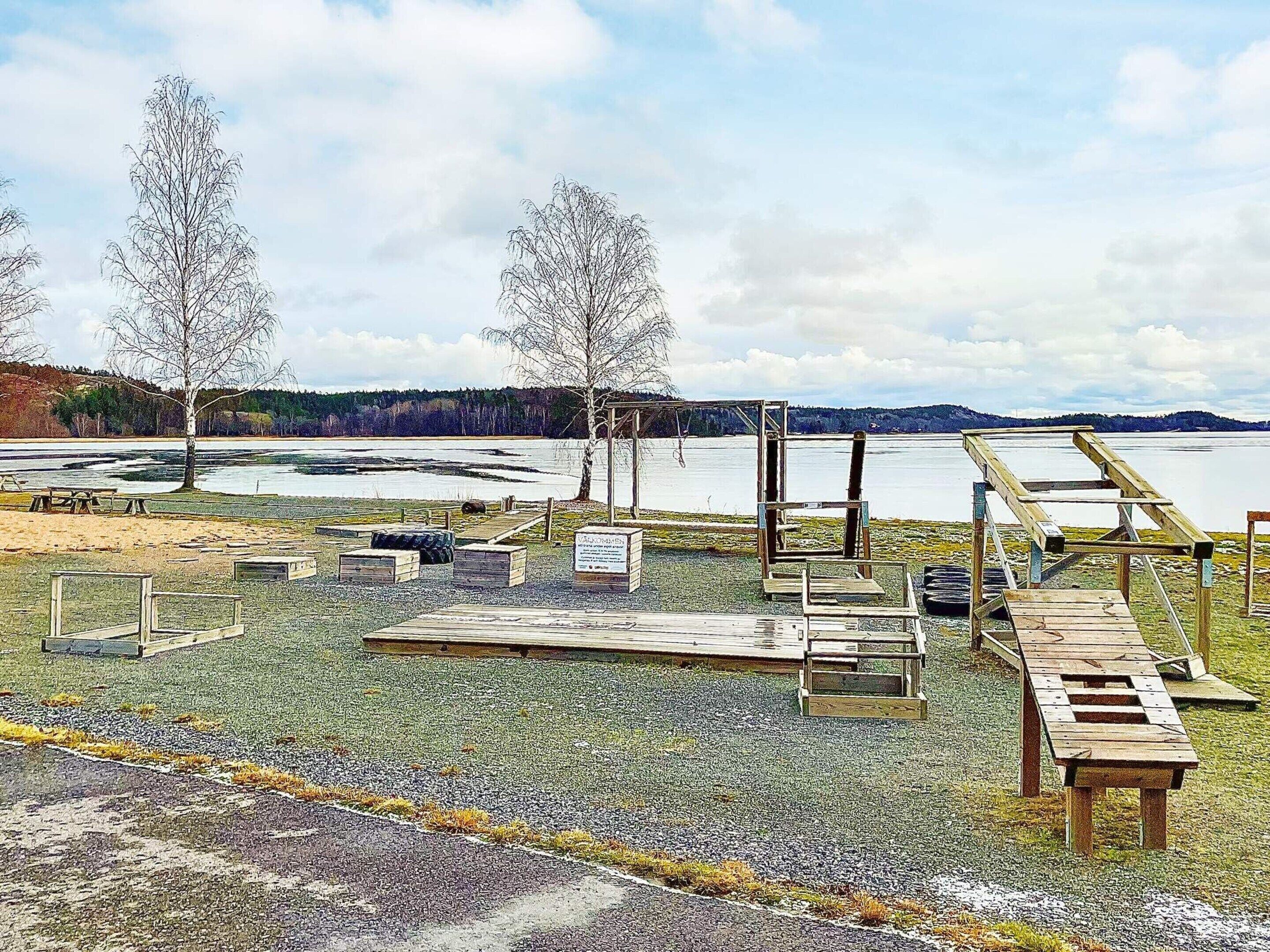 A lakeside park with picnic tables, a wooden deck, and a viewing platform.