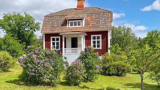 A red house with a tiled roof, a porch, and a garden with purple flowers. - 7 Person Holiday Home in Edsbruk-by Traum (Edsbruk)