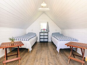 A small, white-paneled attic bedroom with two beds, a small table, and a window. - 6 Person Holiday Home in Vinderup (Vinderup)