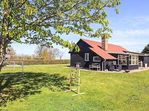 A black building with a red roof, a chimney, and a patio area with outdoor furniture. - 6 Person Holiday Home in Vinderup (Vinderup)