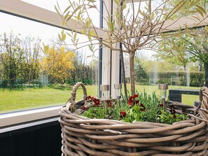 A wicker basket with a plant and flowers, a window, and a view of a garden with trees and a lawn. - 6 Person Holiday Home in Vinderup (Vinderup)
