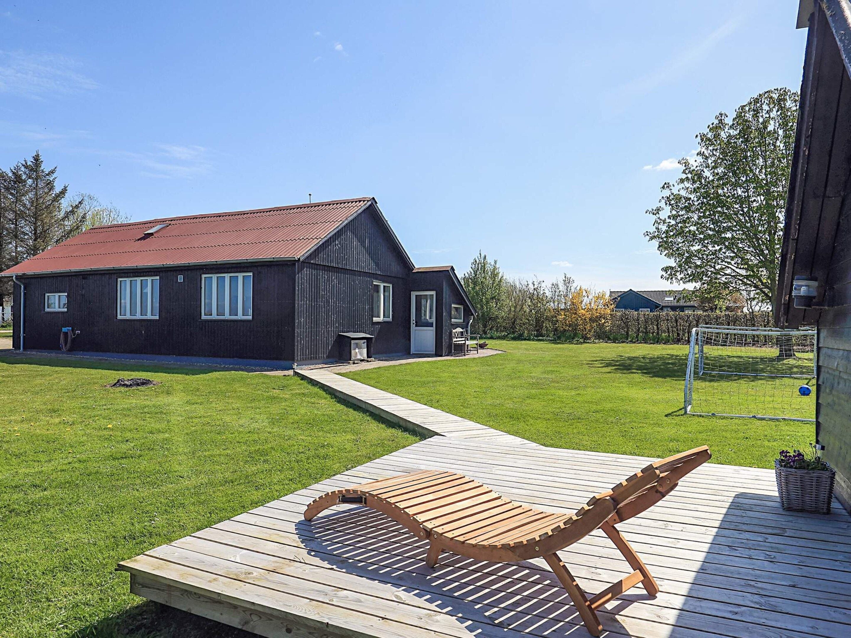 Ein Haus mit Terrasse, Rasen und Fußballtor.