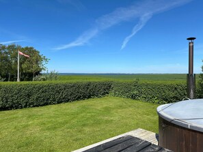 A hot tub on a wooden deck with a clear view of a grassy yard and a hedge. - 6 Person Holiday Home in Vinderup (Vinderup)