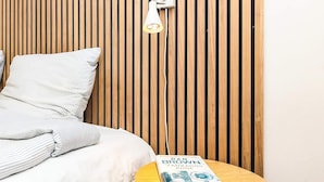 A bed with striped bedding, a bedside table with a book, and a wall with vertical wooden slats. - 6 Person Holiday Home in Vinderup (Vinderup)