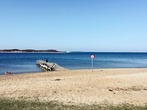 A beach with a pier, a no swimming sign, and a distant boat. - 6 Person Holiday Home in Farso (Farso)