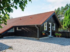 A wooden house with a sloped roof and a gravel driveway.