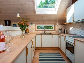 A modern kitchen with wooden cabinets, a skylight, and a view of greenery outside.
