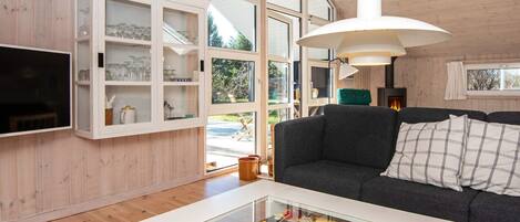 A modern living room with a sofa, a glass coffee table with board games, and a white cabinet with glass doors.