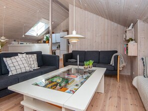 A modern living room with two dark sofas, a glass coffee table, and wooden flooring.