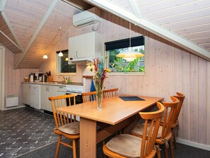 Et hyggeligt køkken med trævægge, et spisebord med stole og et vindue med udsigt til grønne områder.