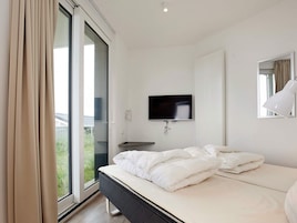 Un dormitorio moderno con cama, televisor y ventana.