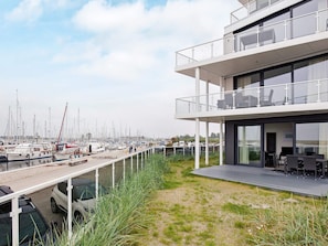 Um edifício moderno com varanda com vista para um porto cheio de barcos.