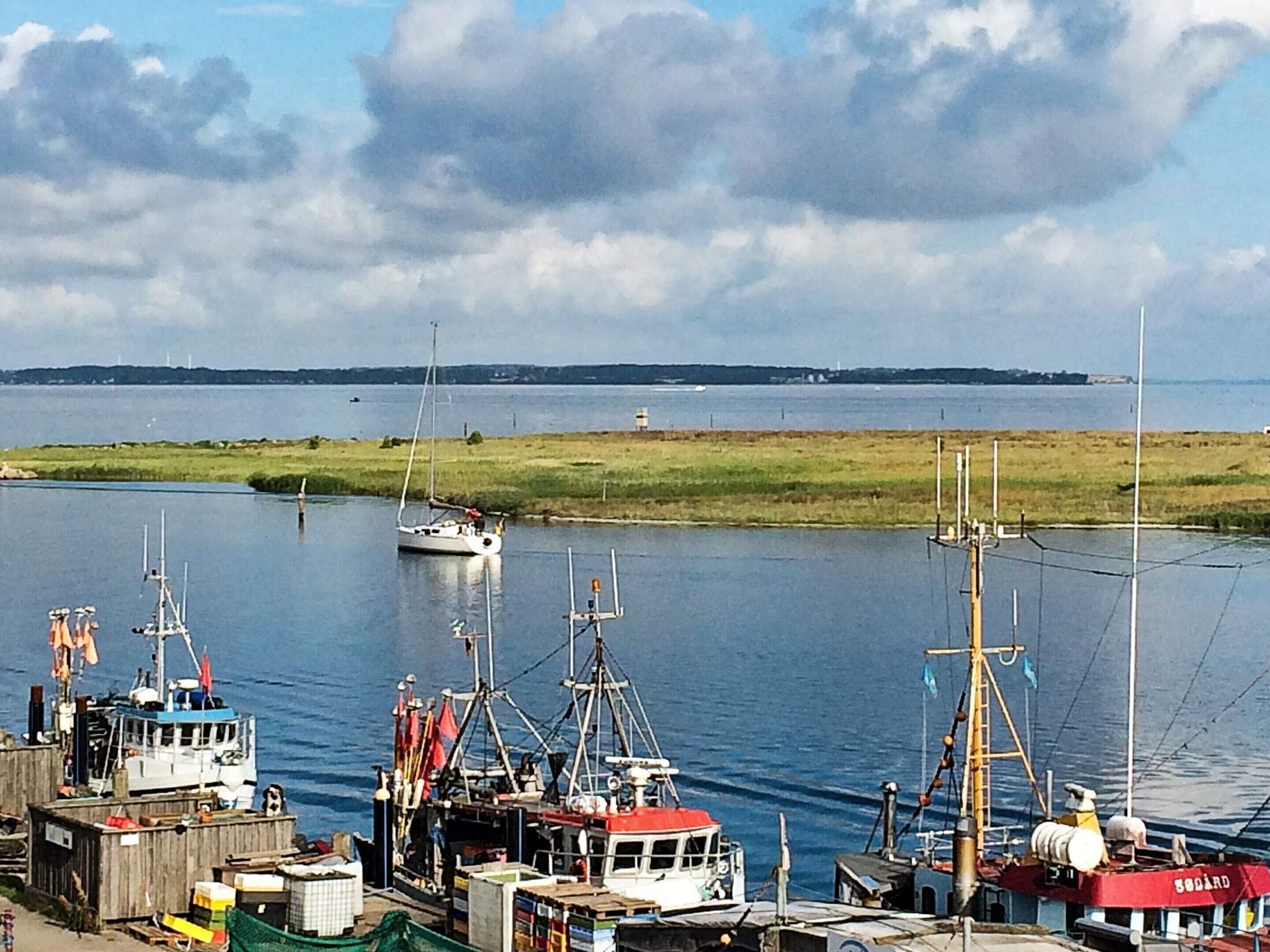 Ein Hafen mit Booten, einem Leuchtturm und einer fernen Küste.