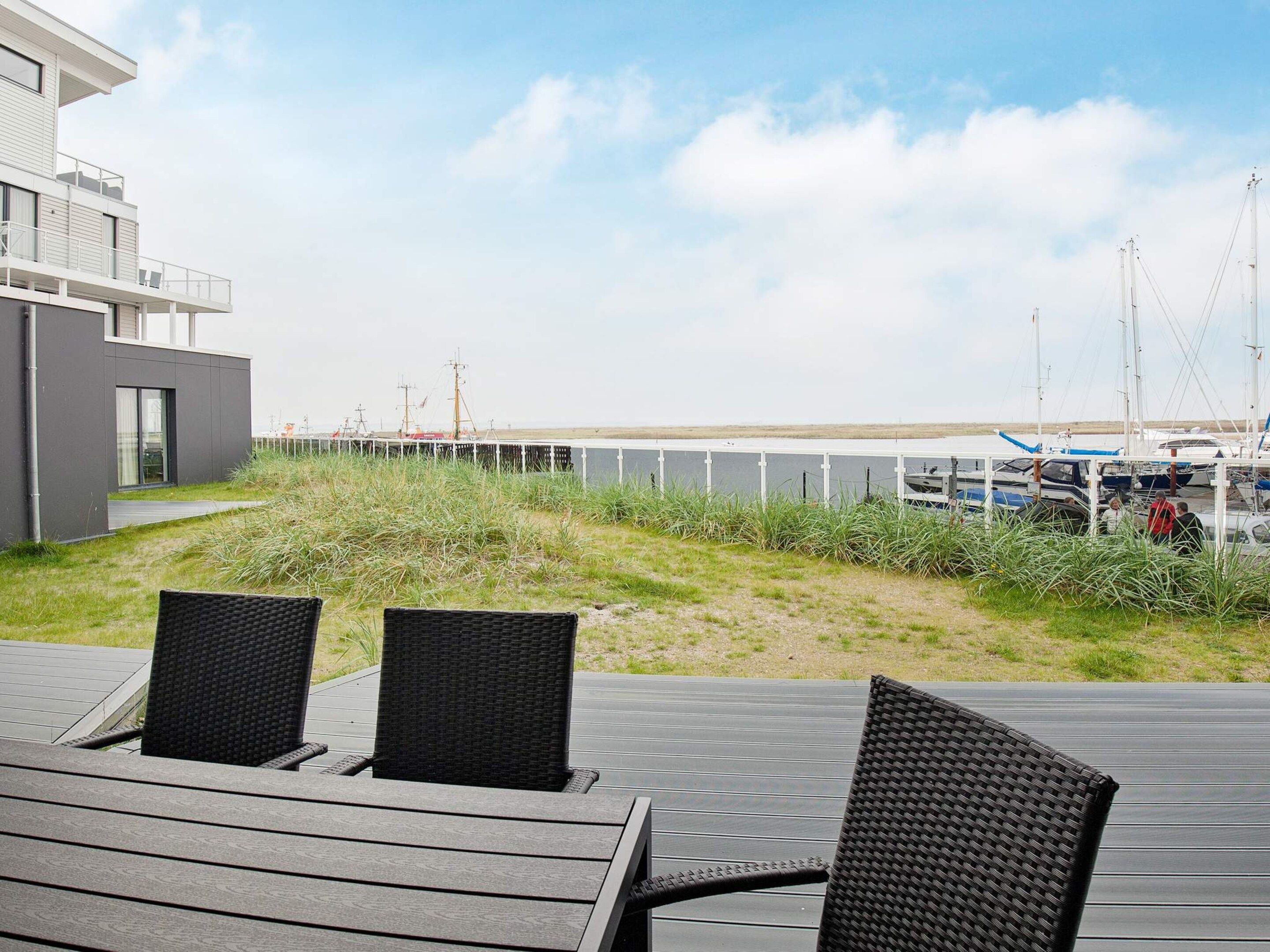 A deck with outdoor seating and a view of a marina with boats.