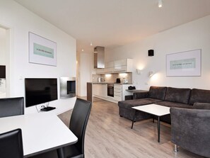 A modern living space with a dining area, a sofa, and a kitchen in the background. - 5 Star Holiday Home in Wendtorf (Wendtorf)