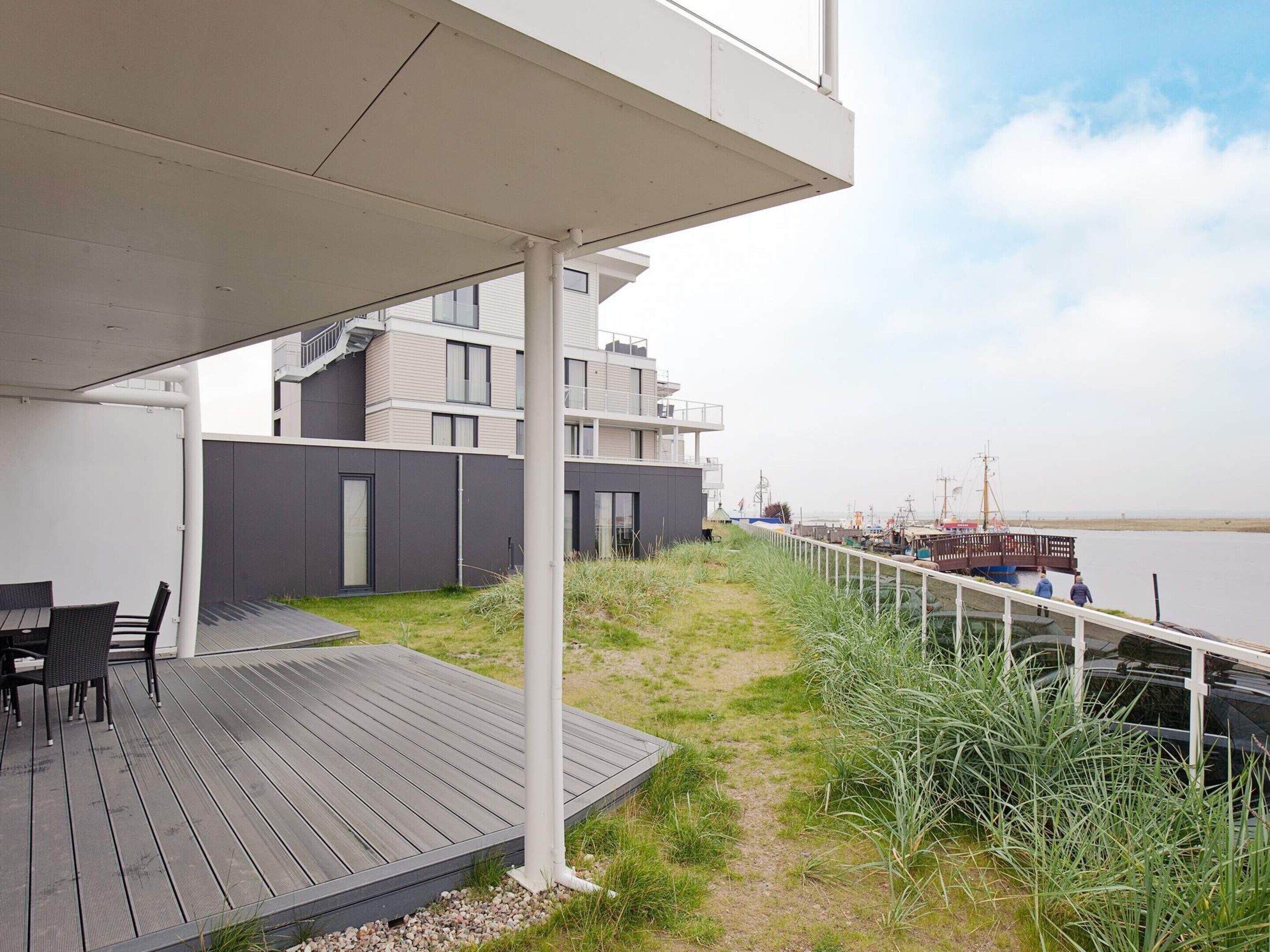A modern outdoor deck with a view of a water body and a building in the background.