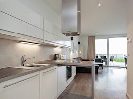 Una cocina moderna con una isla central, electrodomésticos de acero inoxidable y vistas a un balcón.
