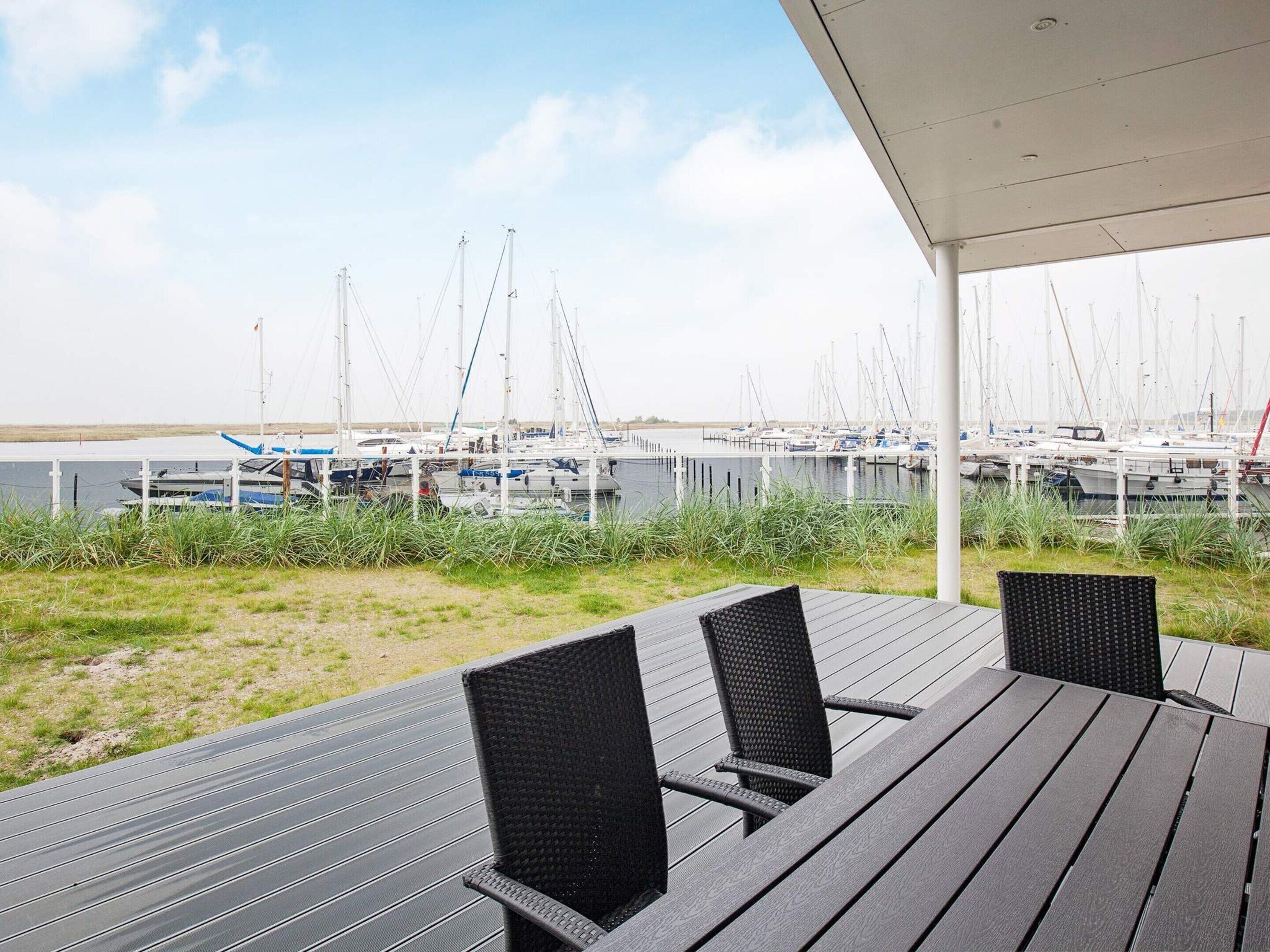 Un espace extérieur aménagé avec des sièges et offrant une vue sur un port de plaisance.
