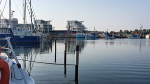 A marina with boats docked, a calm water surface, and buildings in the background. - 5 Star Holiday Home in Wendtorf (Wendtorf)