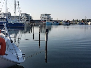 A marina with boats docked, a calm water surface, and buildings in the background. - 5 Star Holiday Home in Wendtorf (Wendtorf)