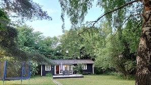 A small house with a porch, a trampoline, and a grassy yard. - 5 Person Holiday Home in Dronningmolle (Dronningmolle)