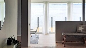 A modern living room with a view of the sea, a sofa, a chair, and a small table with a plant. - Stylish Seaside Villa on Ven-by Traum (Sankt Ibb)