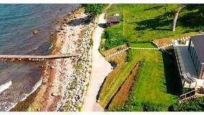 A coastal property with a wooden dock, a paved path, and a grassy area with a building. - Stylish Seaside Villa on Ven-by Traum (Sankt Ibb)