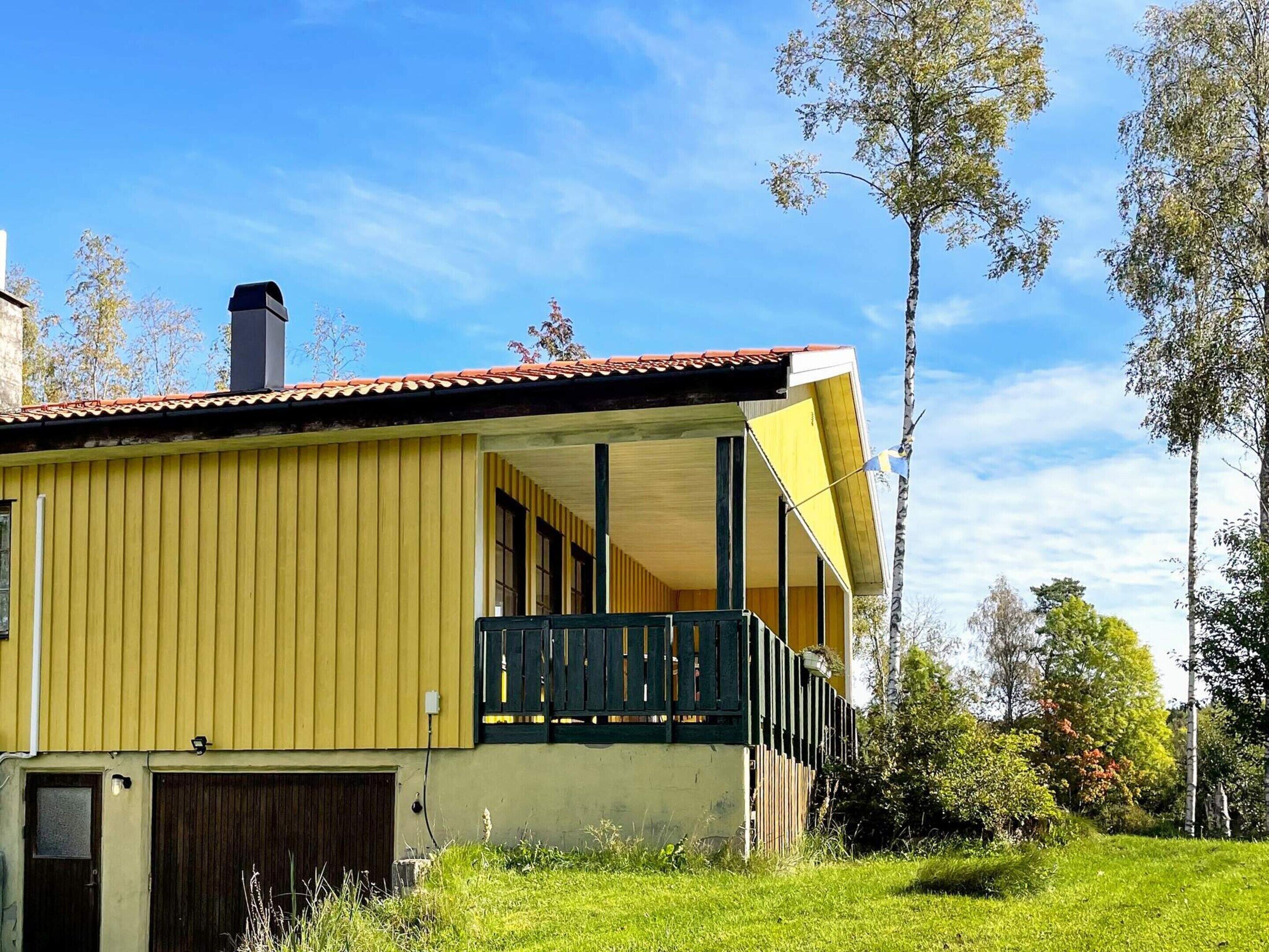 Un edificio amarillo con balcón, chimenea y tejado rojo.