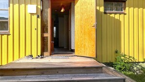 Een geel gebouw met een houten deur en een klein raam.