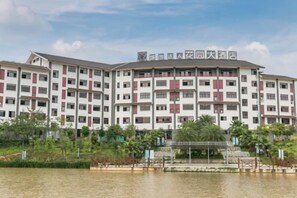 A multi-story hotel with a symmetrical facade, a central entrance, and a surrounding water body. - Chengshi Daren Garden Hotel (Laibin)