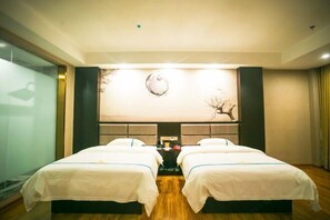 Habitación de hotel con dos camas, un mural grande en la pared y una mesita con una lámpara.
