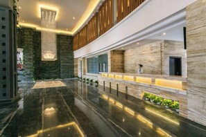 A modern lobby with a marble floor, a reception desk, and a large chandelier. - Chengshi Daren Garden Hotel (Laibin)