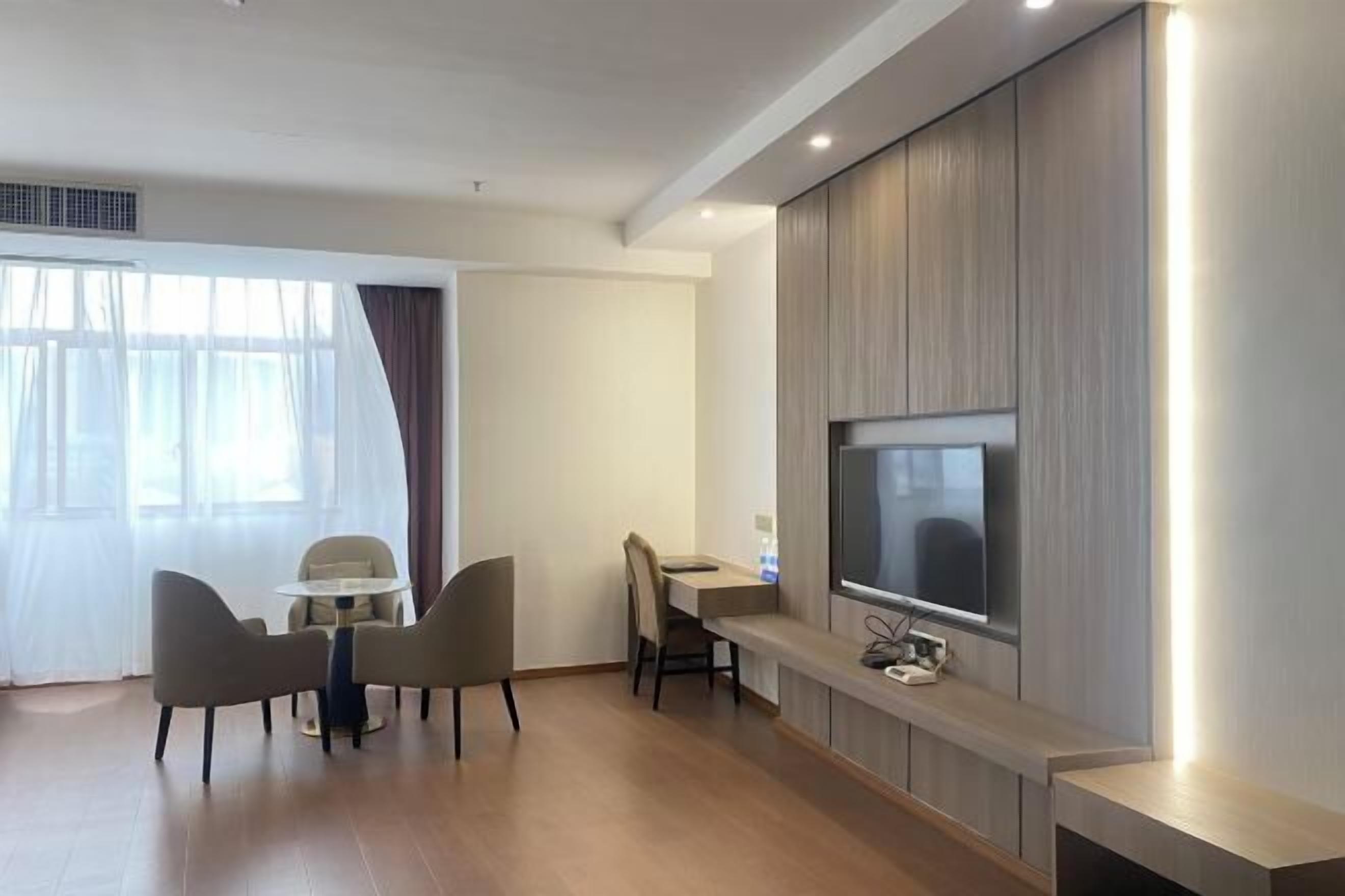 A modern hotel room with a dining area, a flat-screen TV, and a built-in entertainment unit.