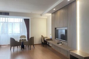 Una habitación de hotel moderna con zona de comedor, televisión de pantalla plana y mueble empotrado para entretenimiento.