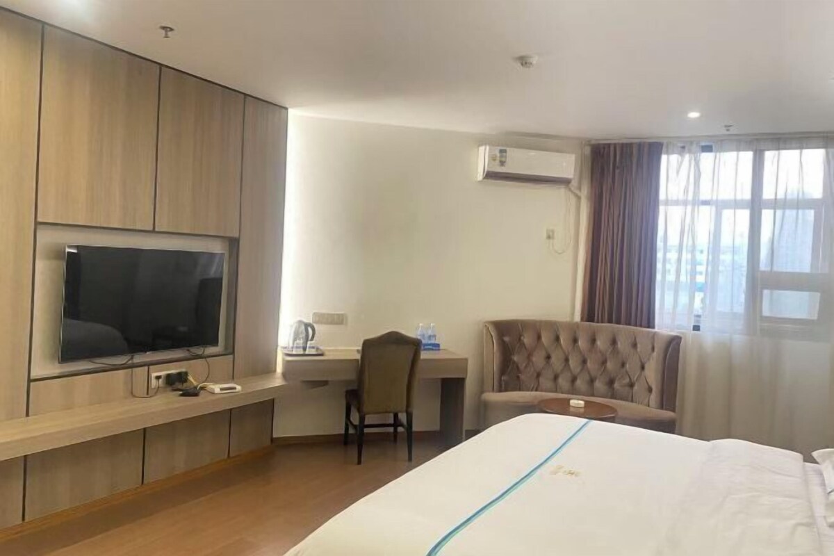 Habitación de hotel con cama, escritorio con silla, televisor montado en la pared y aire acondicionado.
