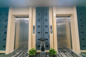 Um elevador com design moderno, apresentando um painel de controle central e dois botões em cada lado.