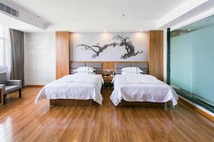 Habitación de hotel con dos camas, un ventanal grande y una obra de arte colgada en la pared.