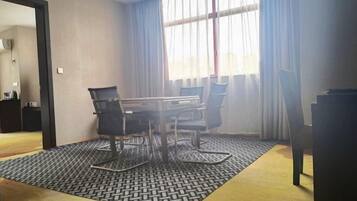 Une salle de conférence équipée d’une table et de chaises, d’un tapis à motifs et d’une fenêtre avec des rideaux.