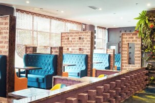 Un restaurante con asientos tapizados en azul, detalles de ladrillo y una pared con estampado.