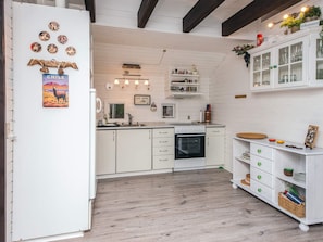 A kitchen with white cabinetry, a stove, and a sink. There are decorative plates on the wall and a sign that says 'CHILE'.