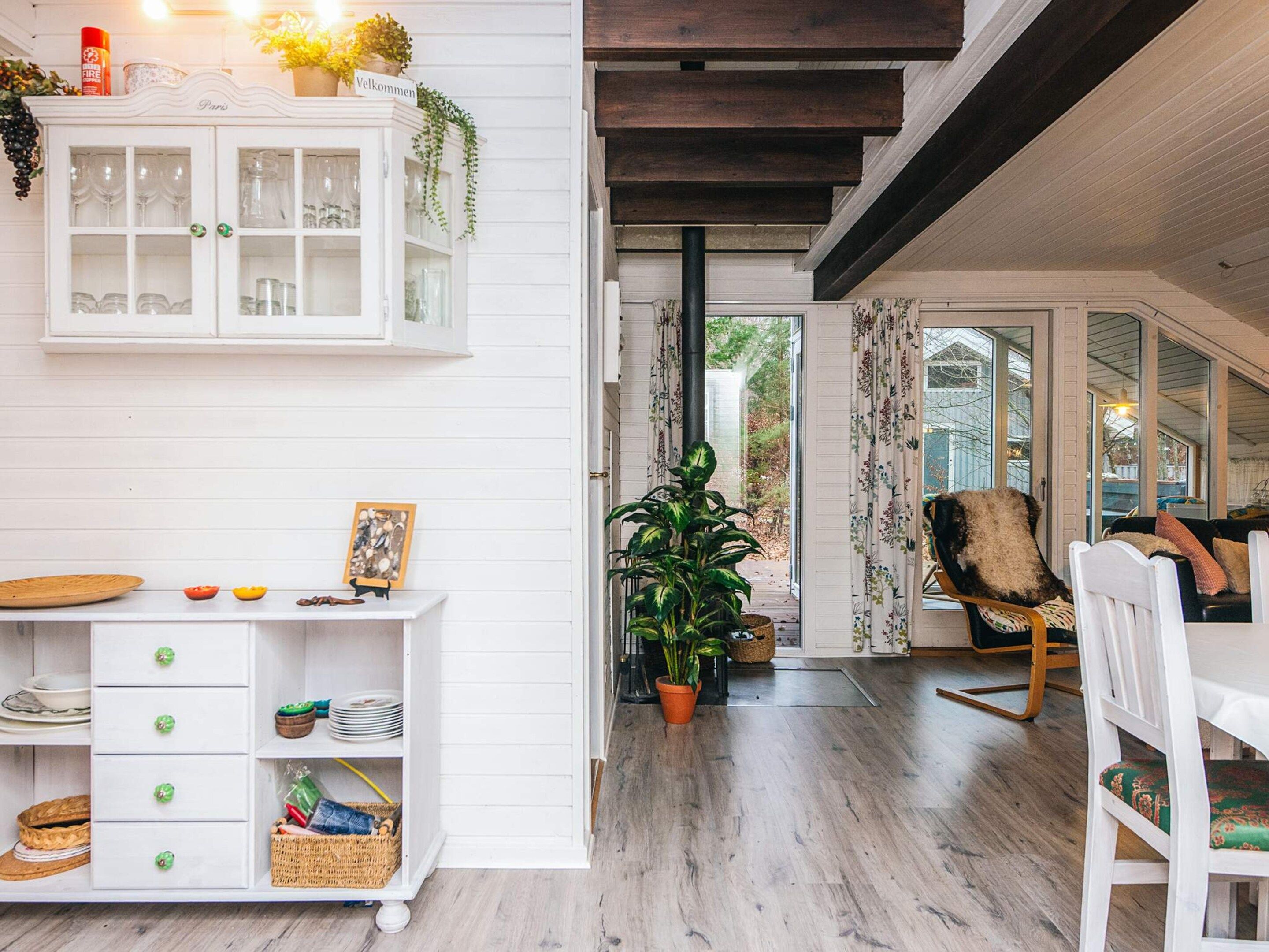 A room with a white cabinet, a wooden dining table, and a large potted plant.
