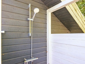 A metal showerhead attached to a wall with a white trim.