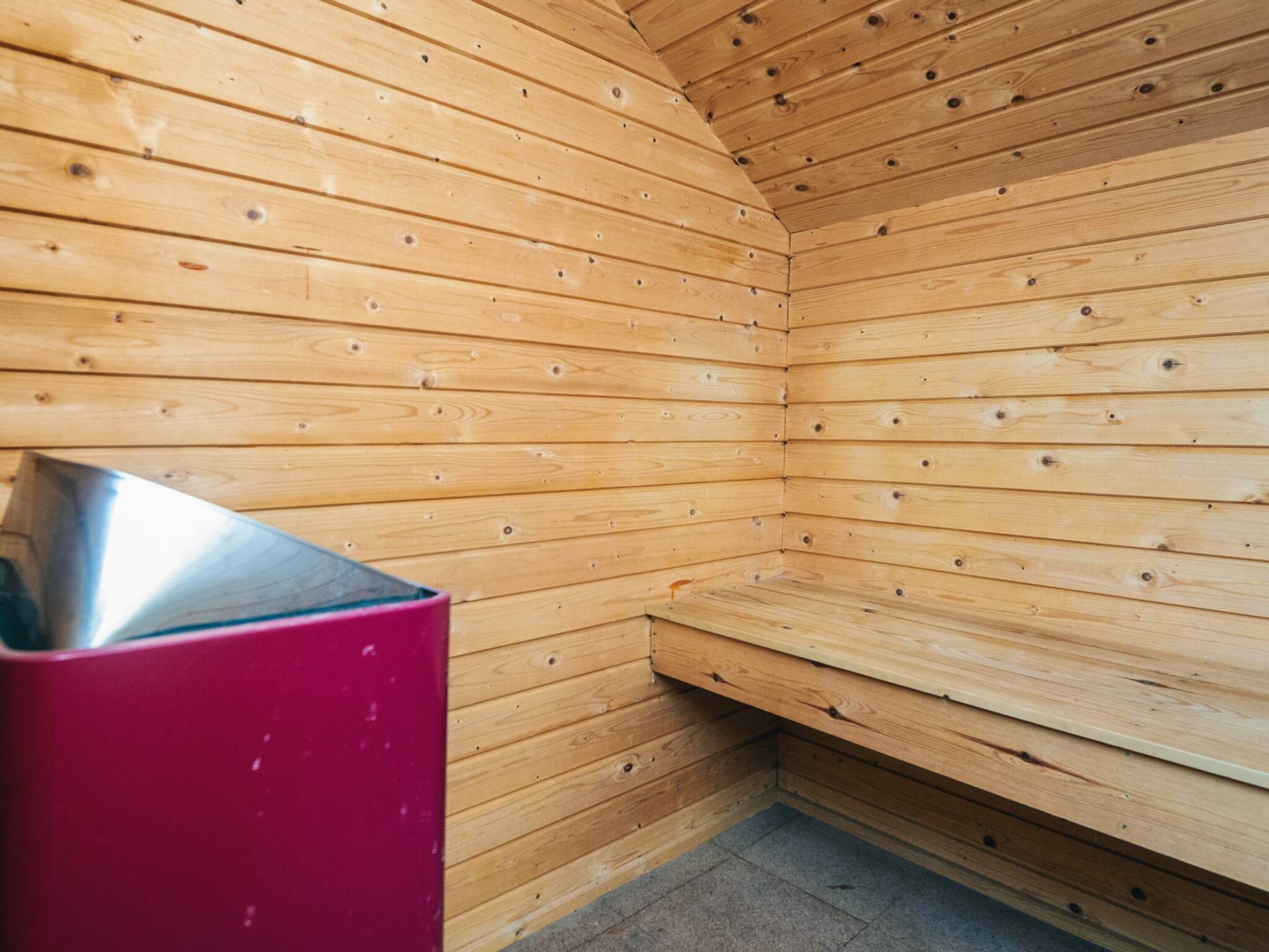 A sauna room with wooden walls and a bench.