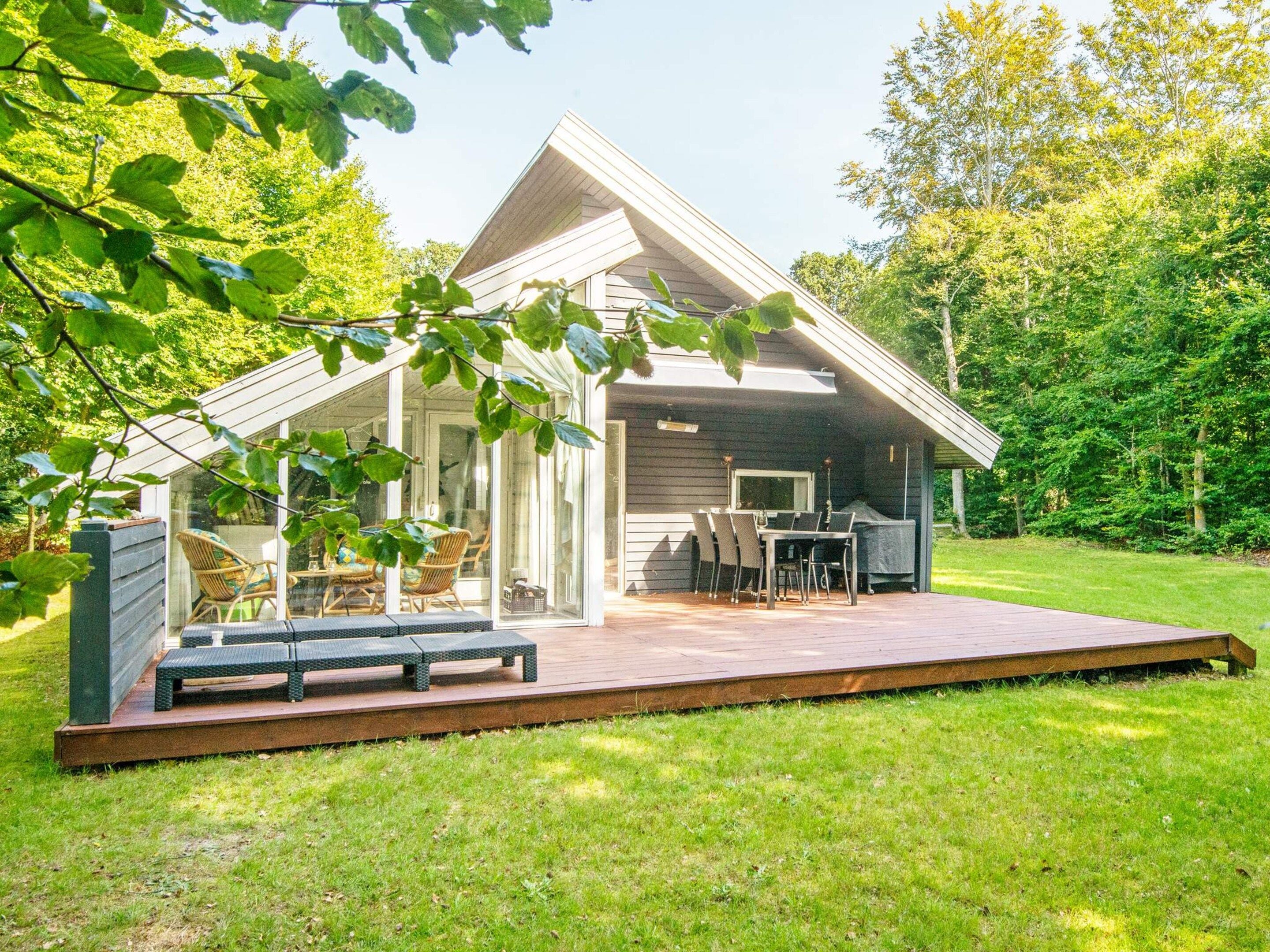 Ein modernes Haus mit Terrasse, Sitzgelegenheiten im Freien und einer Grillzone.