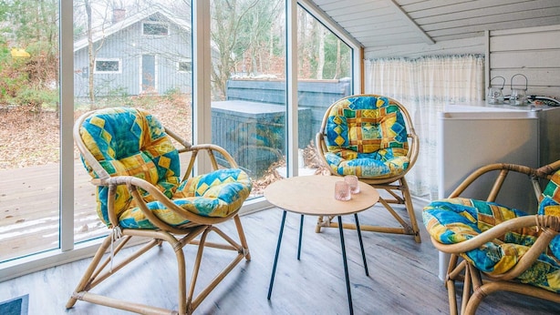 A cozy room with wicker chairs and a round table, large windows offering a view of the outdoors. - 6 Person Holiday Home in Glesborg (Glesborg)