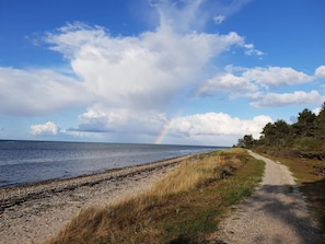 A coastal path with a beach, a rainbow, and a clear sky.
