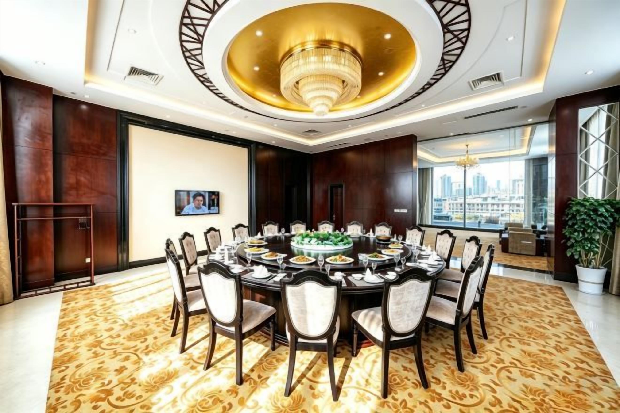 A conference room with a round table, chairs, a chandelier, and a city view.