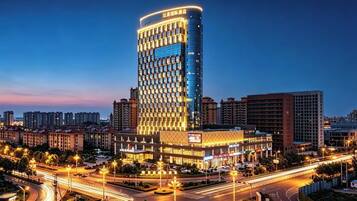 A high-rise hotel with a modern design, surrounded by a well-lit urban area.