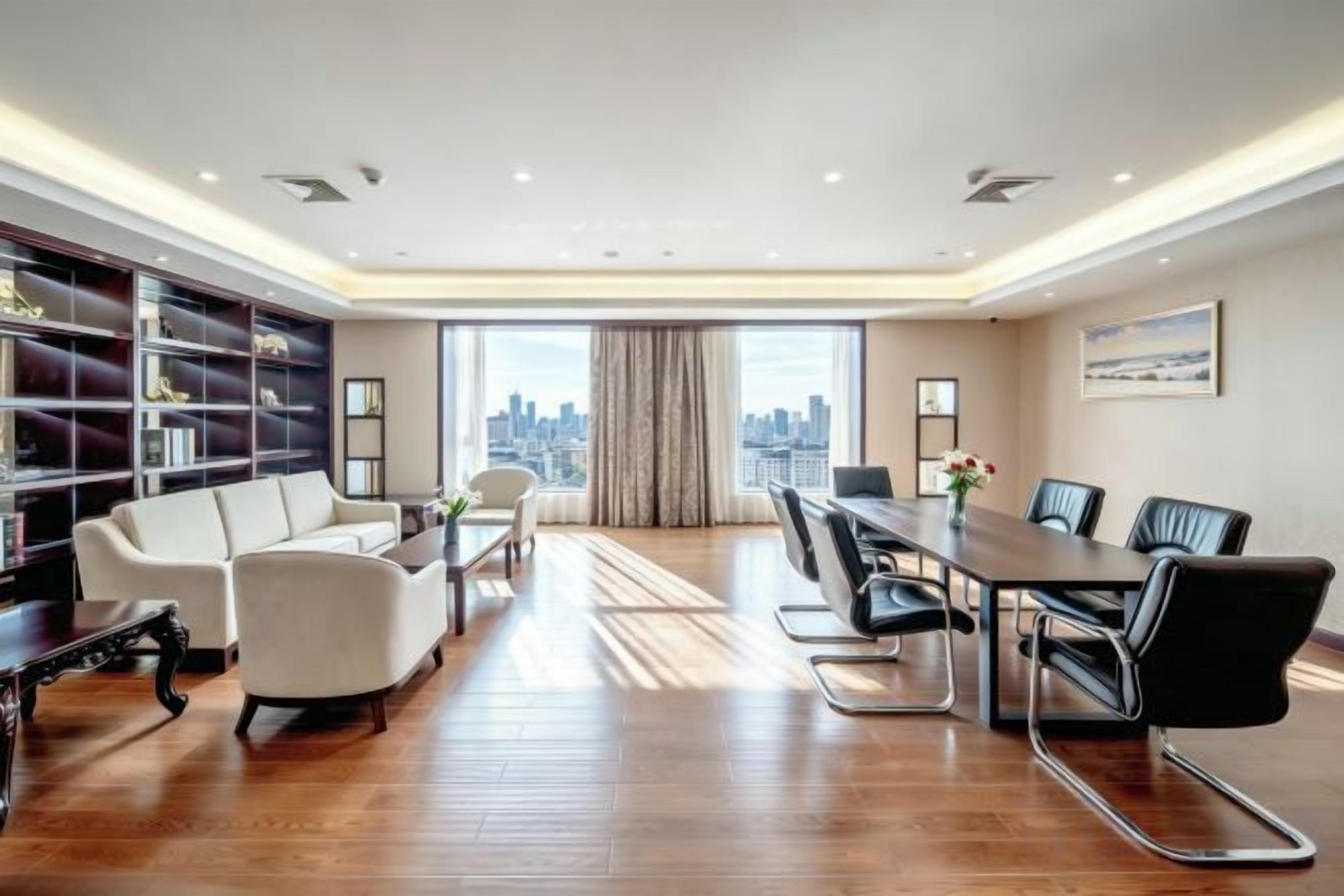 Un cuarto amplio con una gran mesa de comedor, asientos cómodos, una estantería y vistas a la ciudad.