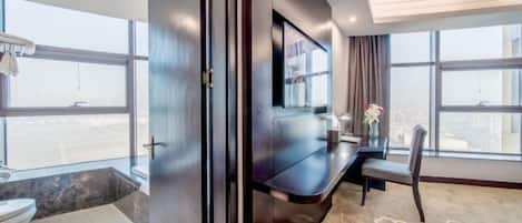 Ein modernes Hotelzimmer mit großem Fenster, Flachbildfernseher, Schreibtisch und Stuhl.